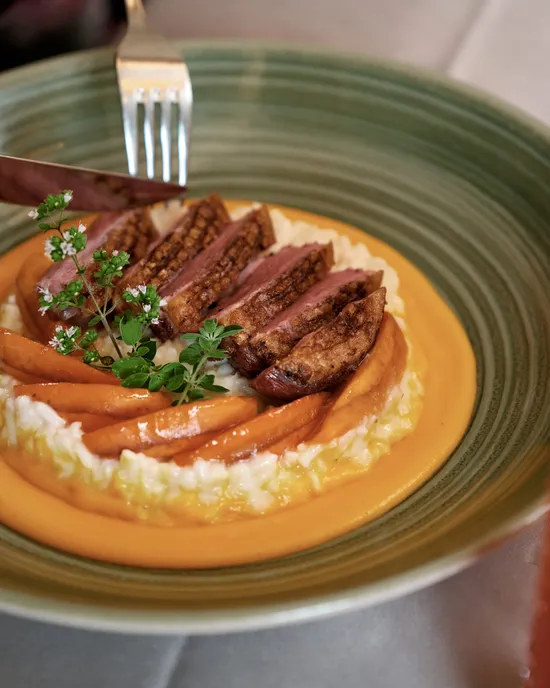 Petto d'anatra gourmet su risotto con carote, erbe aromatiche e salsa arancione cremosa